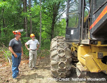 Two loggers looking at harvest equipment.