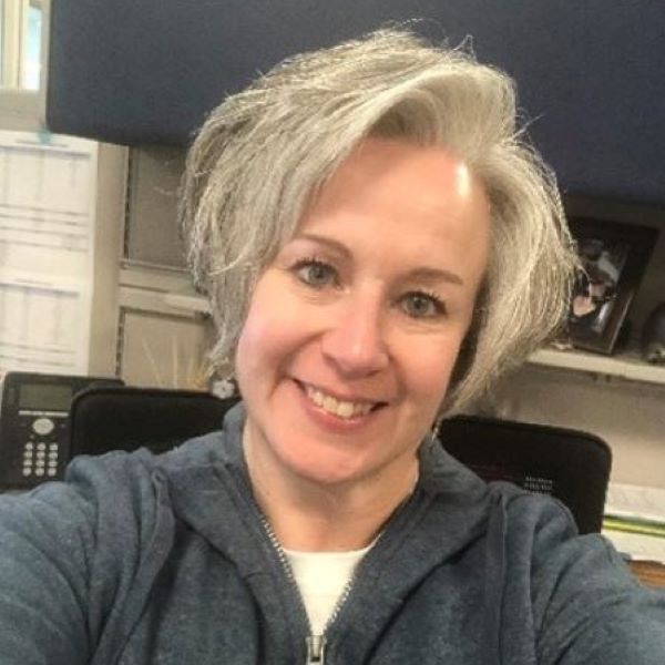 Julie Pelletier smiling, short hair, office cubicle in background