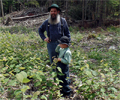 The Nelsons stand in the middle of a recently cleared patch of forest land to discuss forest.