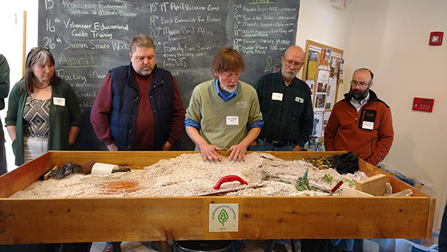 People standing around a table that demonstrates water flow.