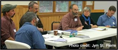 People sitting around a table listening to one of them speak.