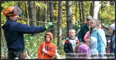 Logger demonstrating using tools in fornt of a group of children.