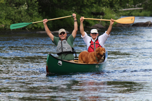 two paddlers and dog finish Chare Rapids on the Allagash
