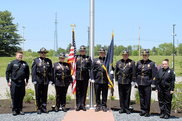 The M D O C Honor Guard stands in formation in front of a flag pole