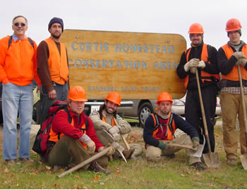 Work crew around Curtis Homestead Conservation Area sign