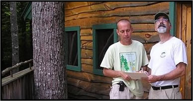 Forester assisting landowner with their management plan in front of a cabin.