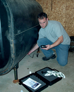Technician measuring the thickness of an aboveground home heating oil tank