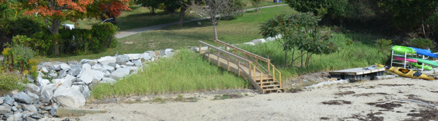 Coastal sand dune restored with multiple levels of coir logs, plantings, and limited riprap that ties into pier infrastructure at Little Diamond Island