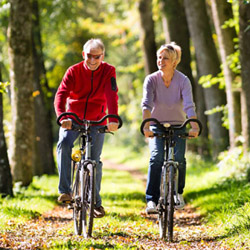 seionr couple biking on wooded trail