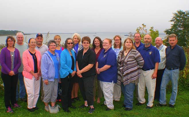 The staff of the Health Inspection Program posing in front of a scenic Maine bay