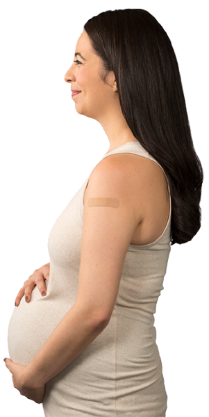 Pregnant woman holding belly, smiling, with bandaid on arm.