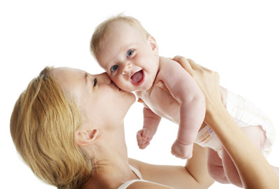 Mom holding and kissing a smiling baby.