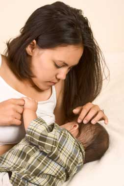 mom holding baby's hand while breastfeeding