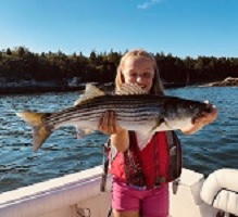 Girl on a boat holding a Striped Bass