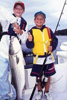 Young boys on a boat holding a Striped Bass