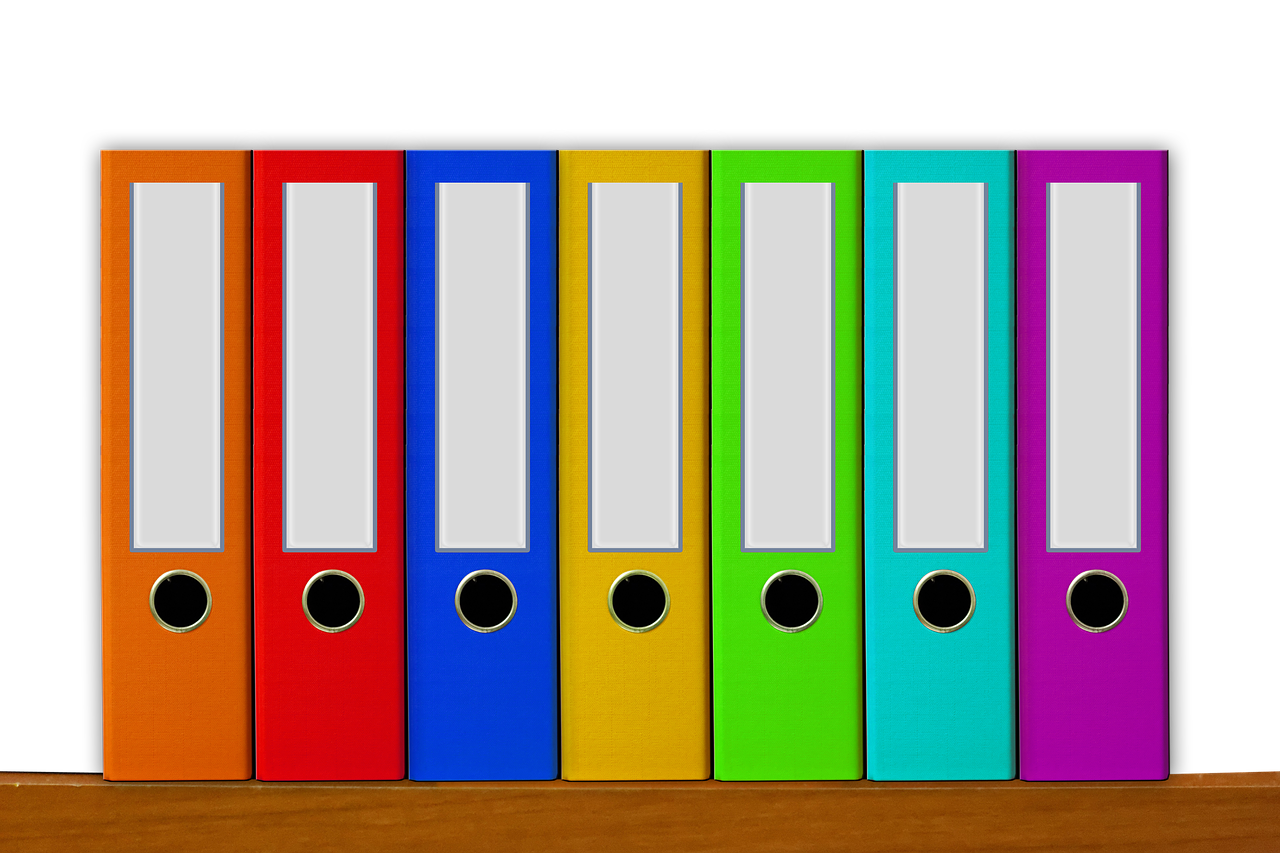 7 colorful binders on a shelf