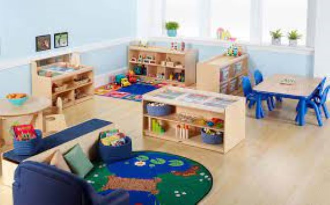 well organized preschool classroom with shelves, rugs, and a table