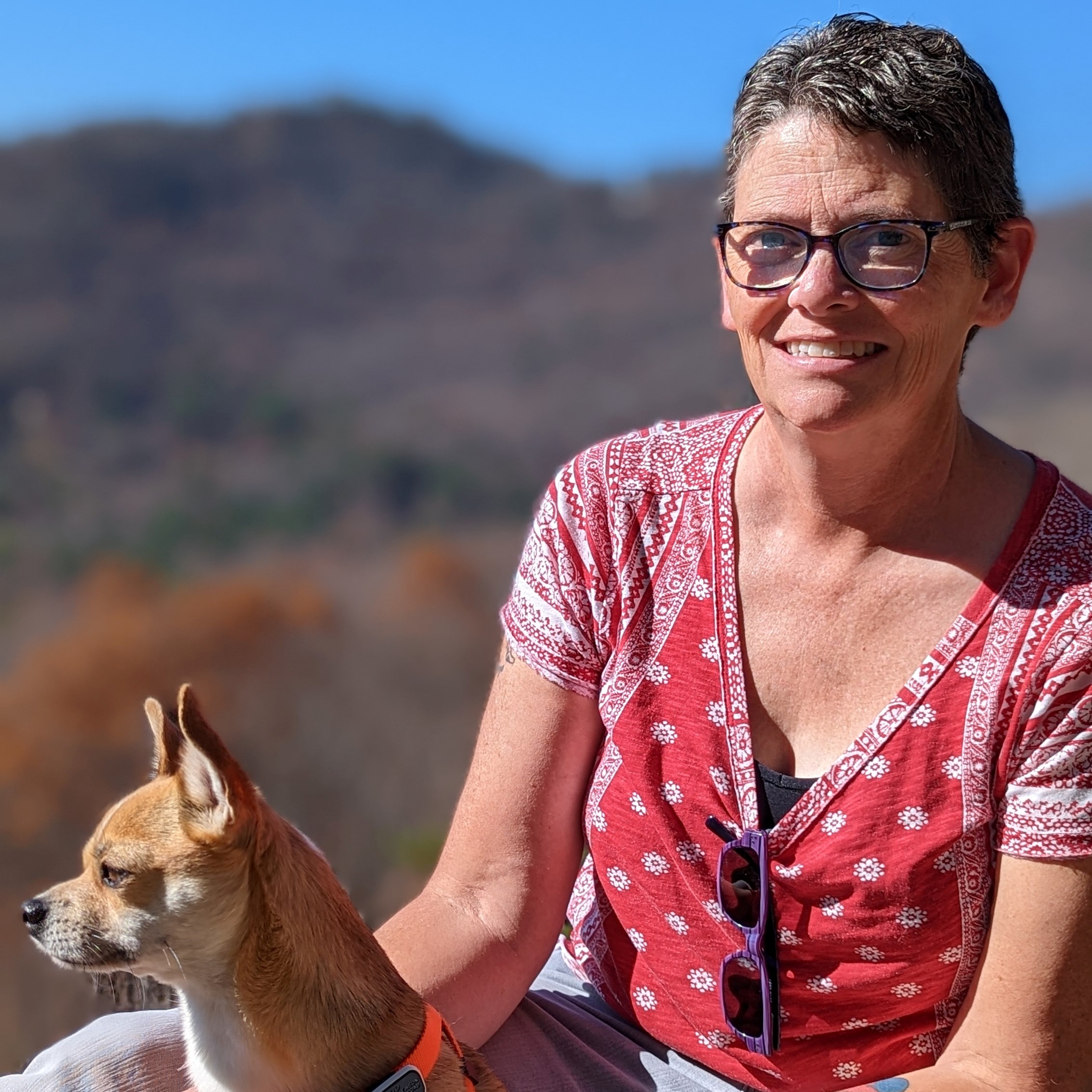Jennifer Gleason smiling, glasses, short hair, outside with dog, mountains in background