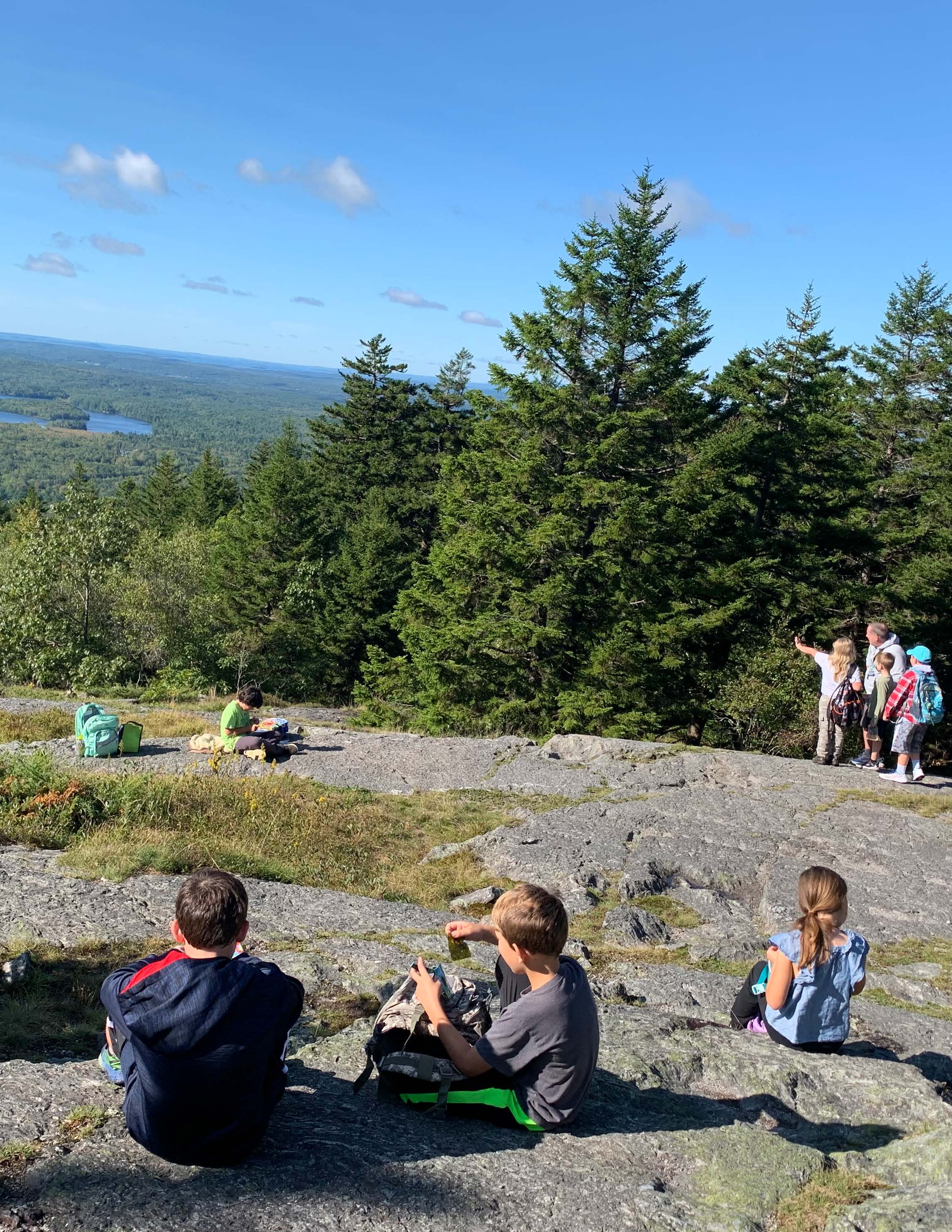 Students and Teachers on a rocky hill top looking out in the distance