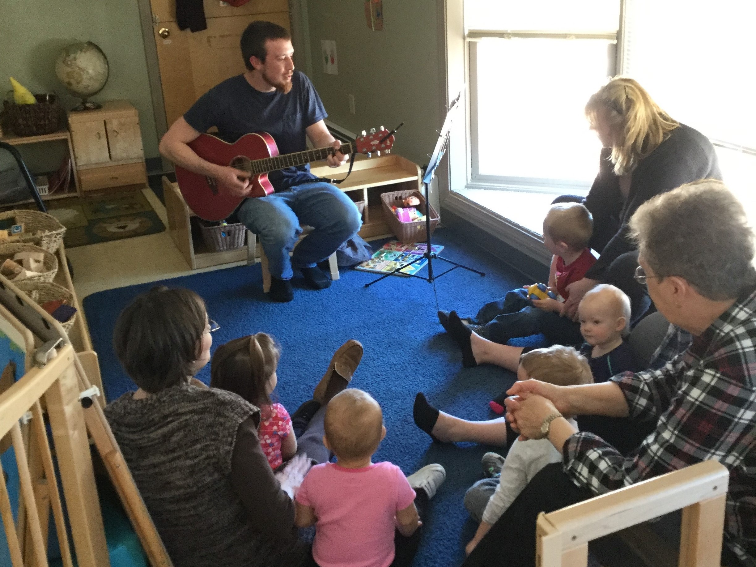 Man playing guitar with families sitting around