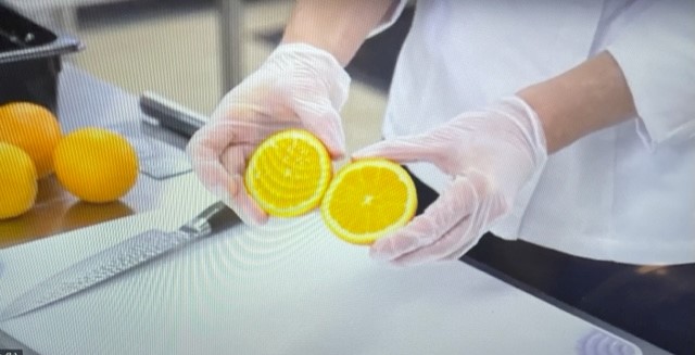 A person holding a lemon cut in half