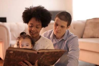 Two adults and child reading book