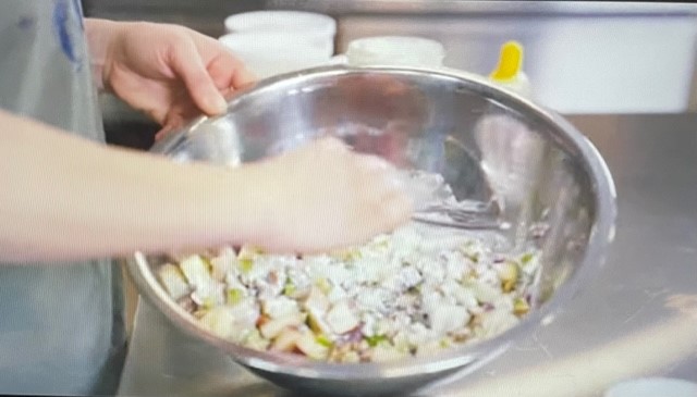 A person mixing a salad in a bowl
