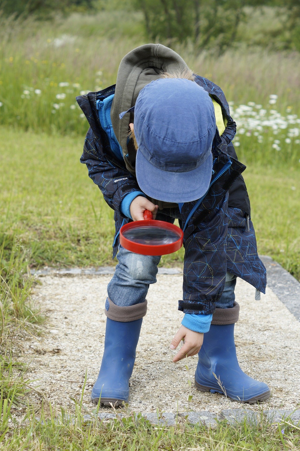 child with magnifier looking at ground