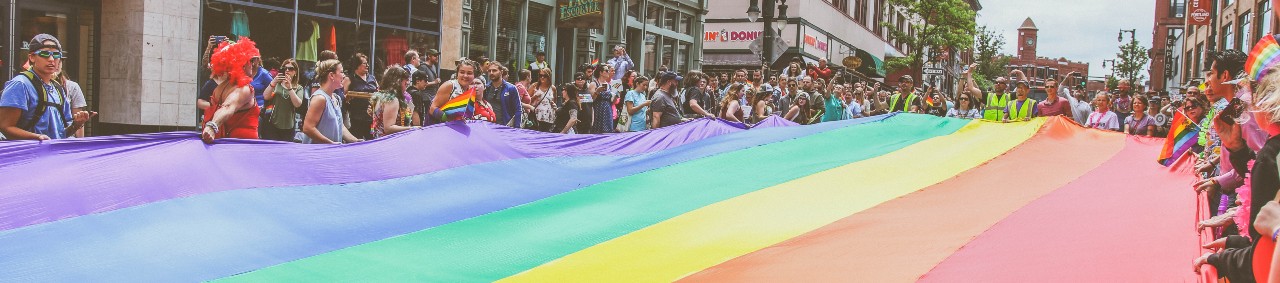 pride parade people holding rainbow flag portland maine