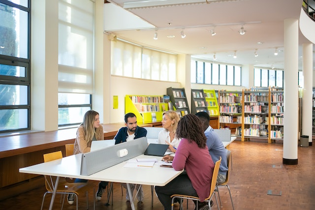 Students gather around table to study and work. 