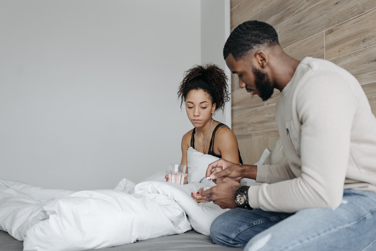 couple in bed man giving woman water