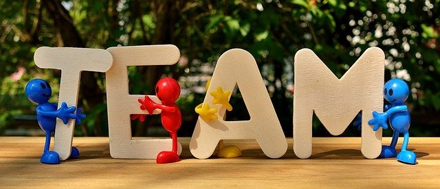 photo of the letters t e a m with little plastic characters scattered around the base.