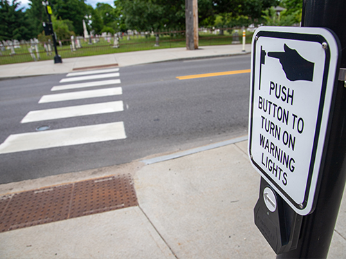 A sign that says to push button for warning lights when crossing the crosswalk