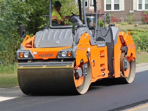 a steamroller driving over fresh tar