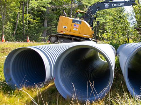 three culverts with a construction vehicle in the background