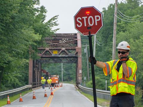 a construction worker holding a stop sign and speaking into a radio