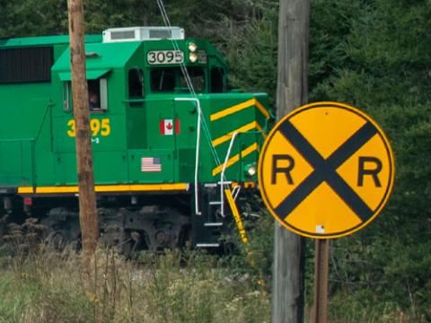 a railroad crossing side with a train in the background