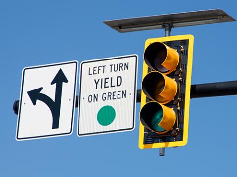 a green traffic light with a "left turn yield on green" sign next to it