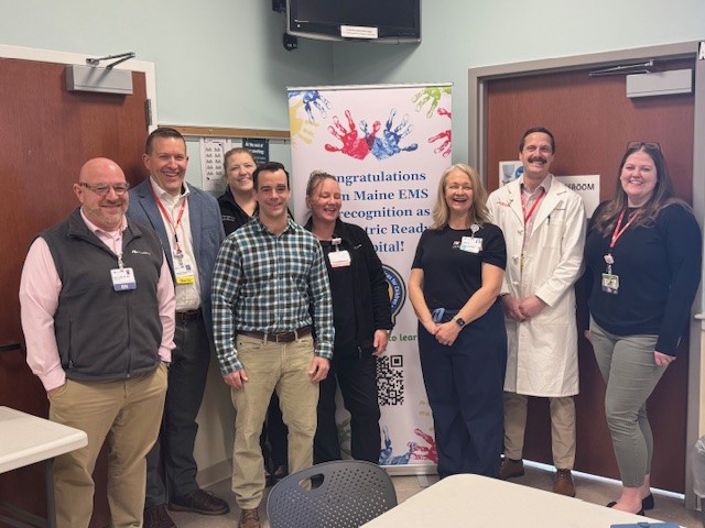 Maine Health Maine Medical Center Biddeford and Sanford ED staff pose in front of banner celebrating recognition as pediatric ready EDs.