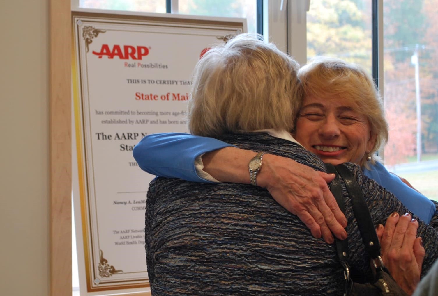 Governor Janet Mills hugging a person at an AARP event, 2019.