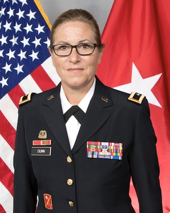 Brigadier General (Ret.) Diane Dunn in uniform, standing in front of a U.S. flag.