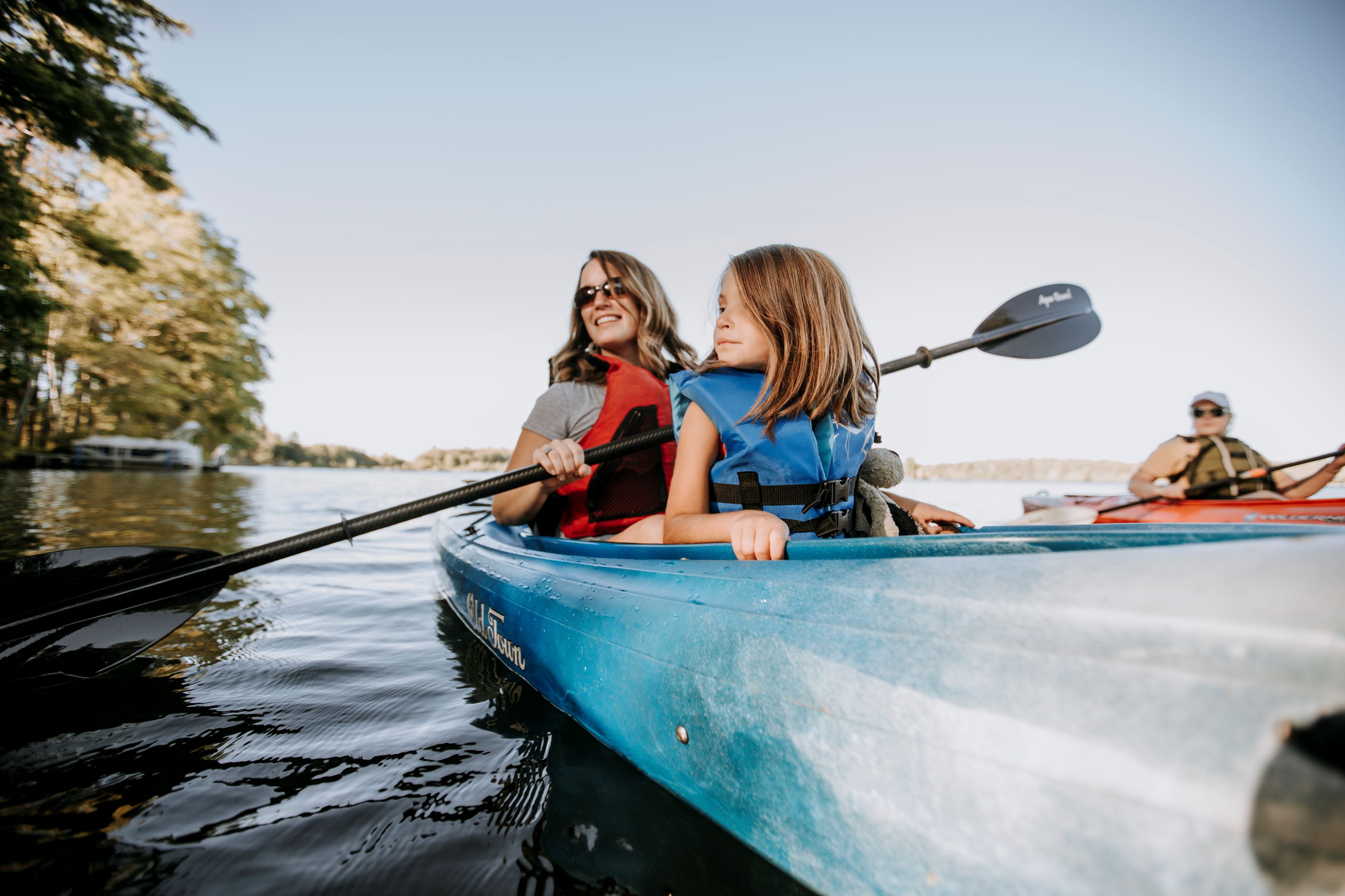 mother and young daughter smiling in blue kayak