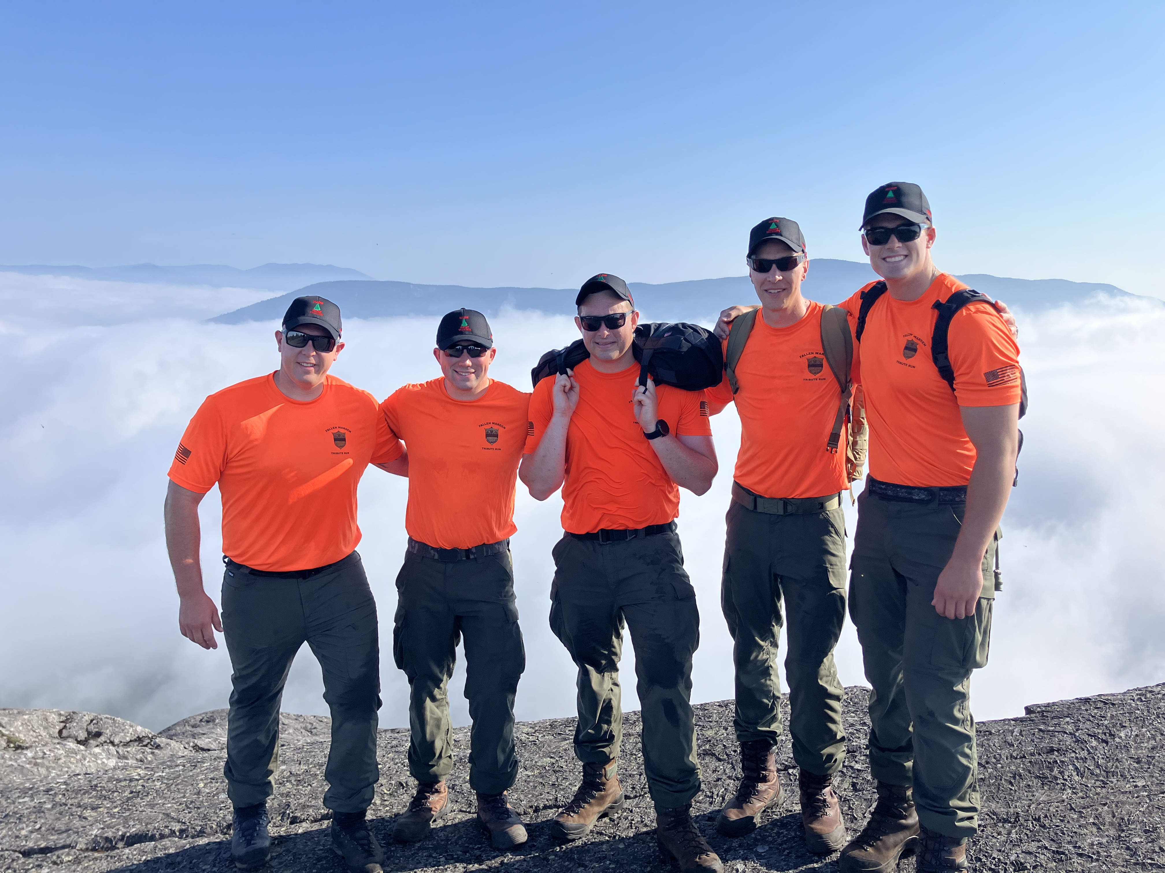 Group of five wardens on top of mountain with blaze orange shirts