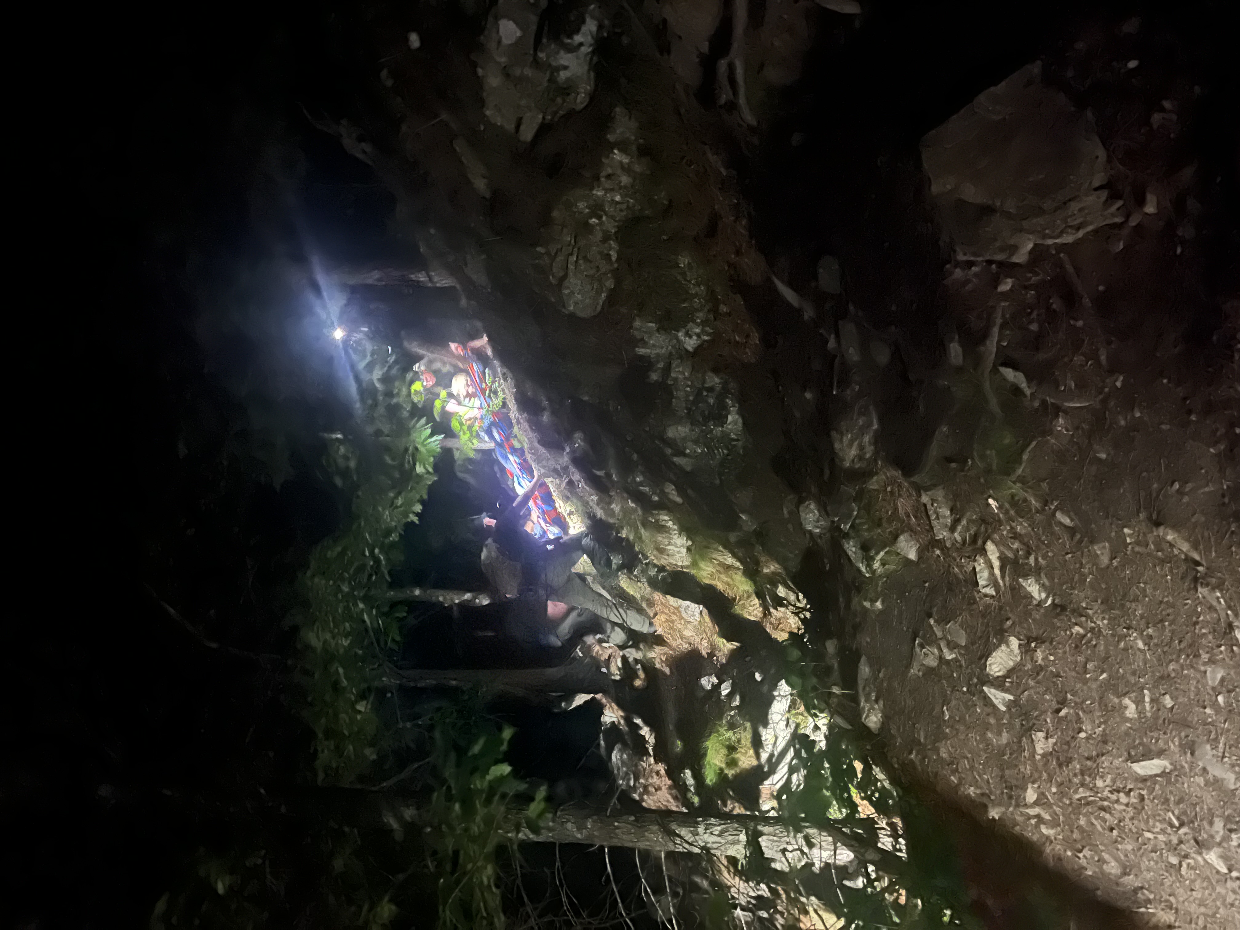 wardens on a steep rocky incline at night wearing headlamps during a mock training