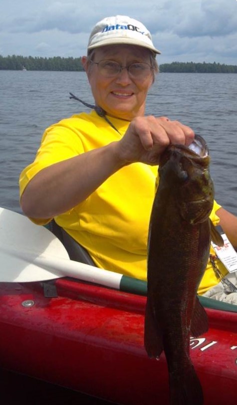 MDIFW's first female fisheries biologist holding up a fish while in a kayak