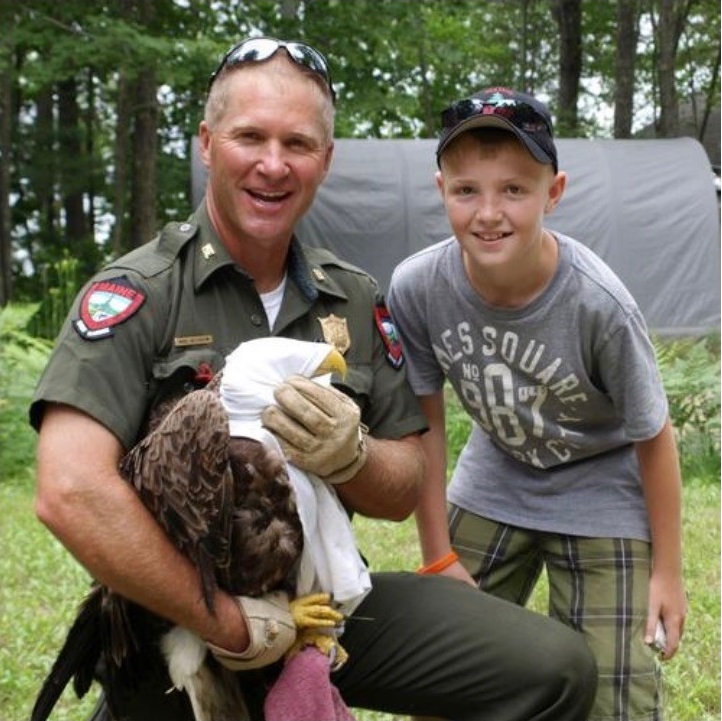 Warden Hutcheson and his son holding bald eagle they rescued