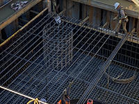 Iron workers moving rebar into position for the top mat of reinforcing in the pier pilecap. The smaller hoops of rebar are for the drilled shaft reinforcing, the larger hoops of rebar are for the pier itself.