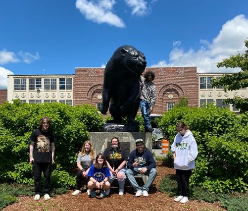 This is a picture of students in front of a bear statue.