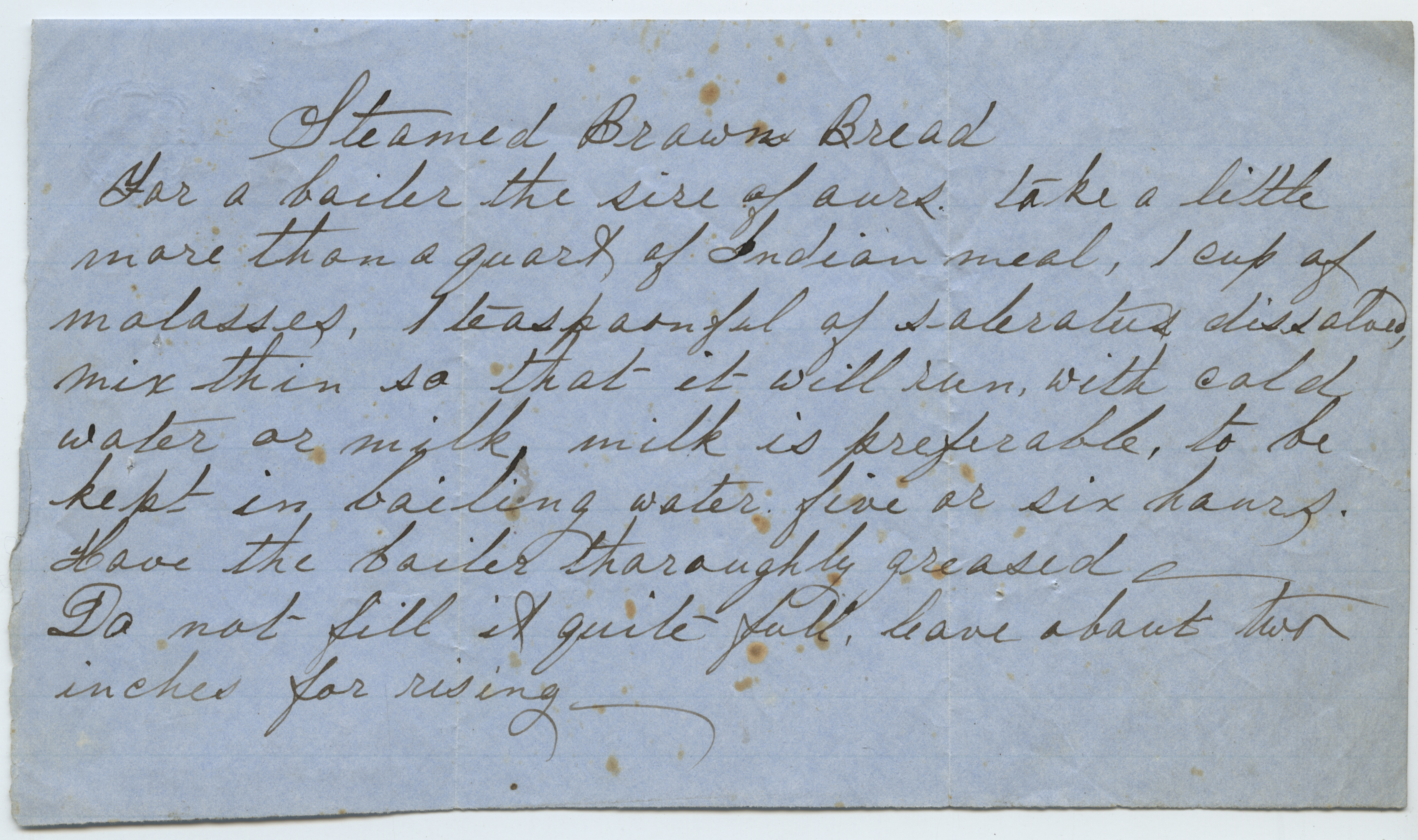 A historic recipe handwritten in ink on aged, light blue paper. The title at the top reads "Steamed Brown Bread," followed by a detailed list of instructions and ingredients including Indian meal, molasses, and saleratus dissolved in water or milk.