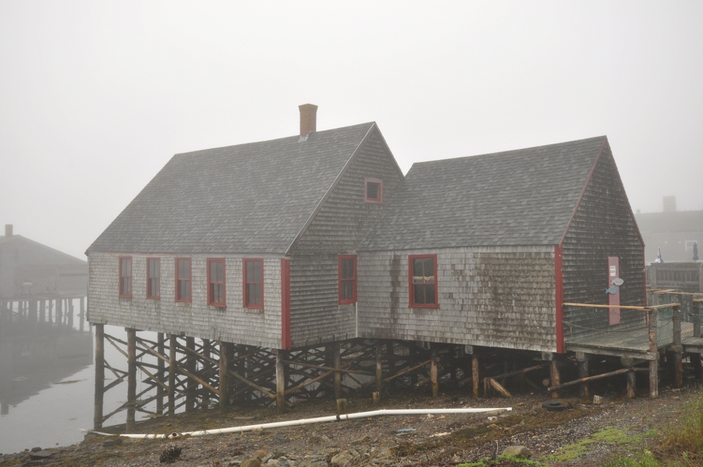 Building sitting on stilts above a river, surrounded by fog